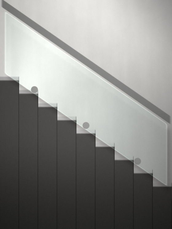 A frameless glass balustrade climbing a flight of stairs on round standoff fixings, with a slim metal handrail above it.
