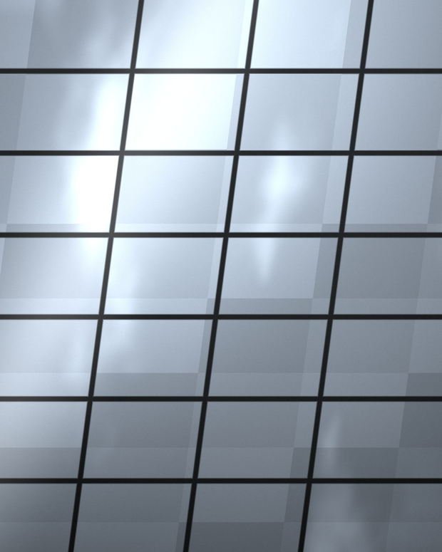 A raking view up a glazed facade, sky and cloud breaking across the panels between dark mullions.